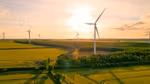Windturbines located in a large grassland landscape with the sun shining.