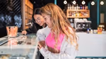 Two friends choosing an ice cream from a retail ice cream cabinet