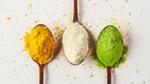 Three spoons holding the yellow, white and green variants of Algenuity’s microalgae rich protein powder