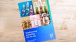 Unilever Annual Report and Accounts 2024 booklet placed on a light wooden desk, featuring product images of Persil detergents, Liquid I.V. hydration packets, Magnum ice cream, Dove body care, and Hellmann’s mayonnaise. The cover text reads “Brightening everyday life for all.”