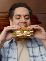 A man prepares to take a bite from a huge ham salad sandwich with mayonnaise.