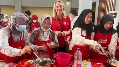Hanneke standing behind women cooking