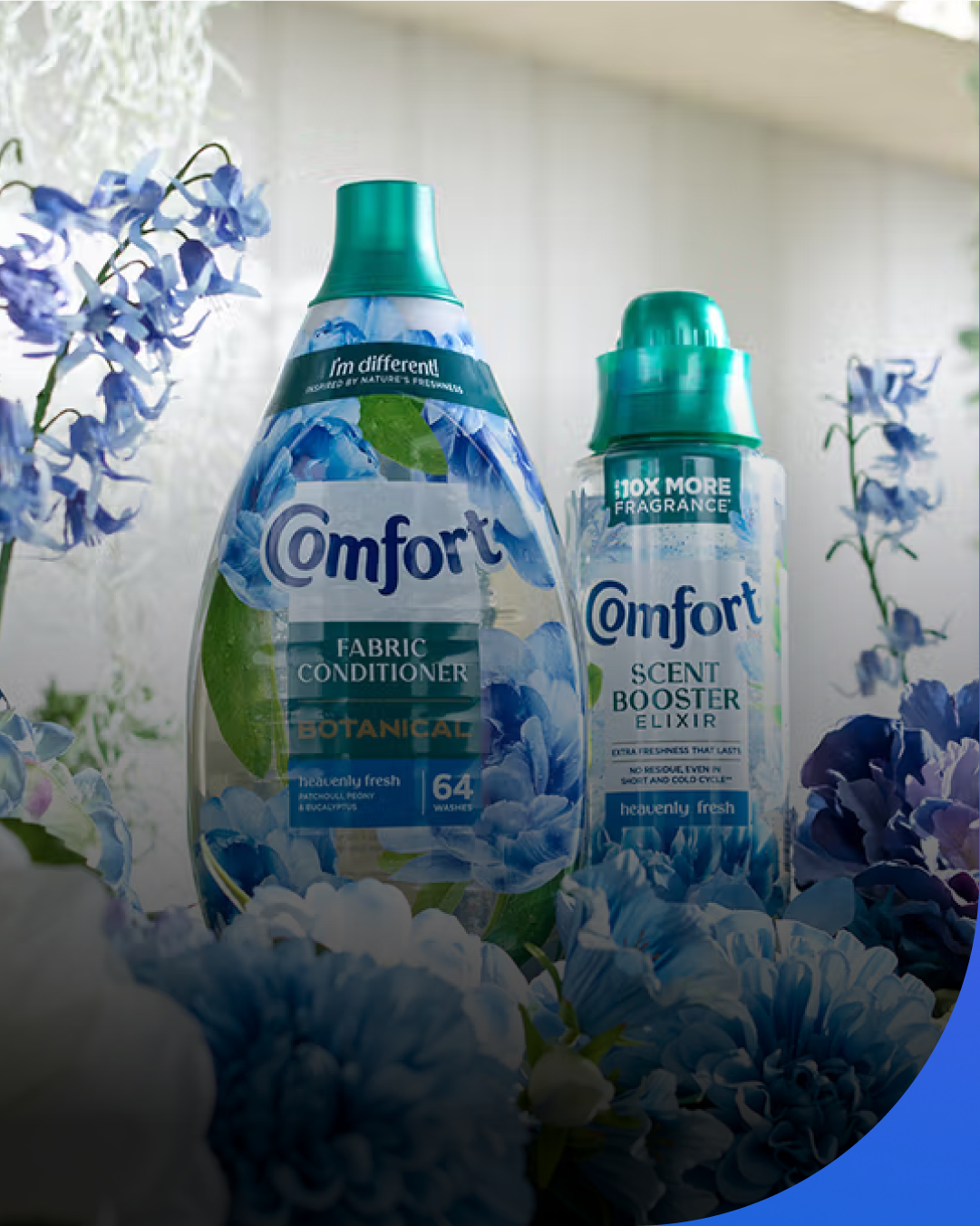 Comfort fabric conditioner and scent booster bottles surrounded by blue flowers, presented in a fresh, bright setting.