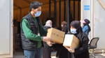 Aid worker wearing a mask giving boxes of Unilever hygiene products to a woman wearing a mask in Jordan