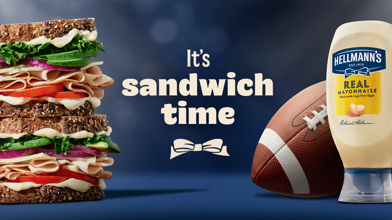 A stacked turkey sandwich with lettuce and tomato sits on the left, with the phrase ‘It’s sandwich time’ in large text at the centre. On the right is a bottle of Hellmann’s Real Mayonnaise next to an American football.