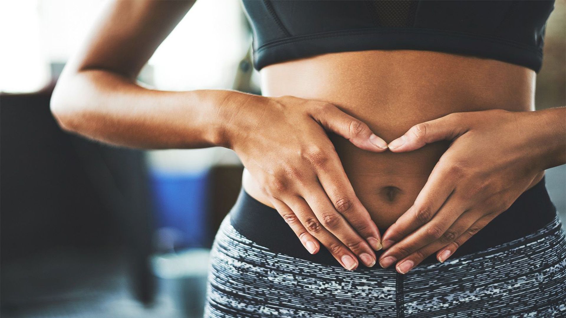 Woman making a heart shape with her hands over her stomach