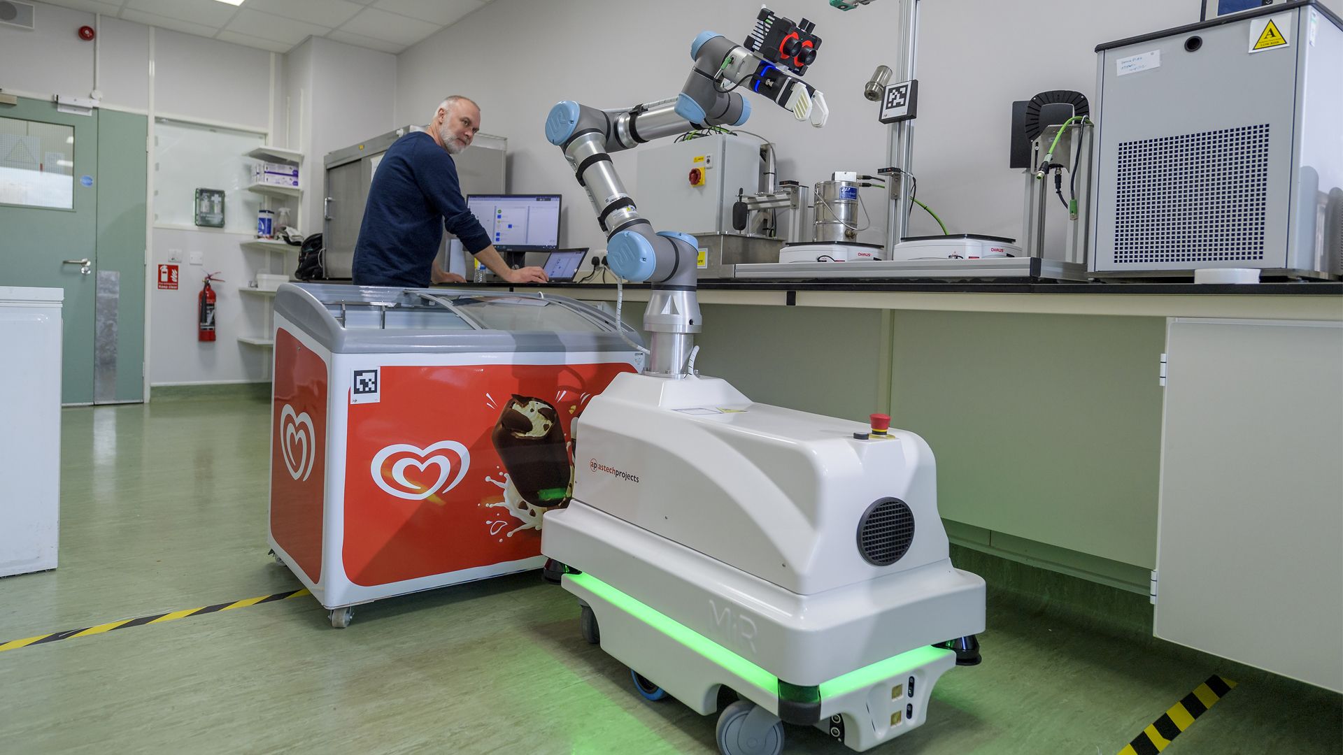 A robot in front of a red Wall's ice cream freezer