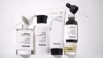 A variety of Minimalist products – a clear glass jar with a dropper, a white plastic bottle with a black lid, a white plastic tube with a black lid, a brown glass bottle with a dropper and a small tub.