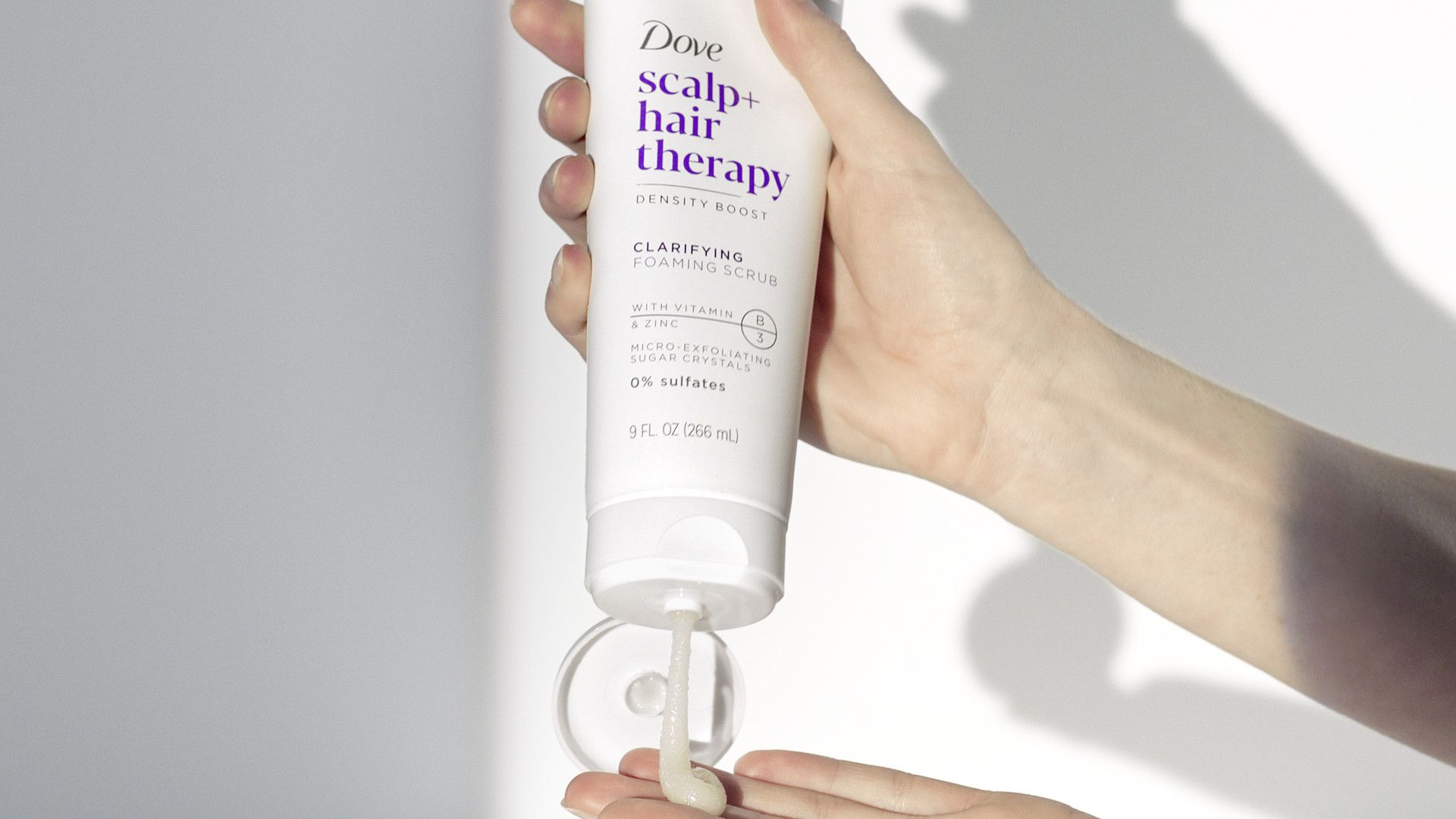 White product being squeezed out of a Dove scalp + hair therapy bottle.