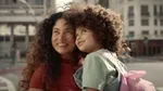 A shot of a woman holding a little girl from Dove’s film ‘The Code’. They have curly brown hair and are looking up, smiling.