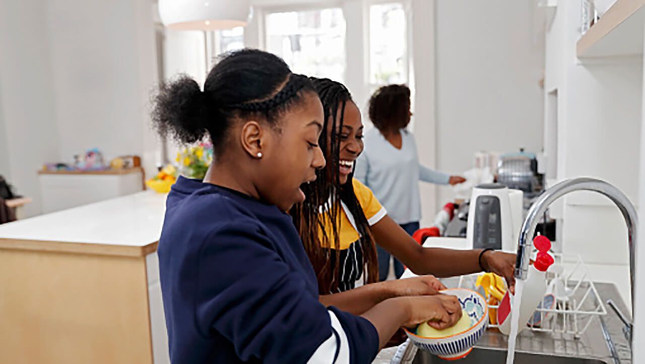 Two smiling girls washing up