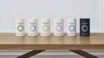 A row of six Nutrafol hair and skin supplement products arranged in a row on a table. Five products are white, one is black.