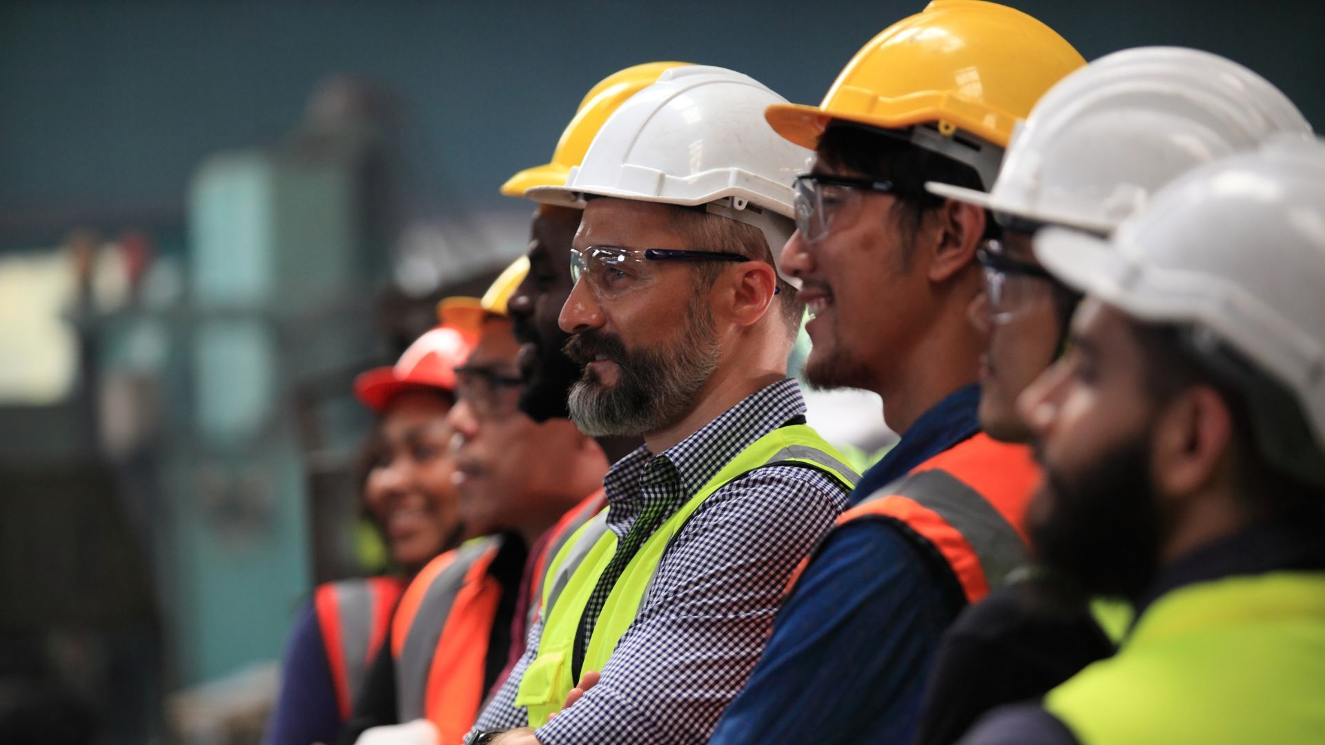 Smiling workers in hard hats and high-visibility clothing