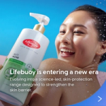 A bottle of Lifebuoy Anti Acne body wash is held in the foreground against a blue background, with water droplets visible around a person’s shoulder. Text on the image reads: ‘Lifebuoy is entering a new era – evolving into a science-led, skin-protection range designed to strengthen the skin barrier.