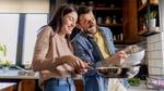 Couple smiling and cooking together in a kitchen.