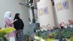 A photograph of two female students observing a Unilever rain harvesting installation at an Islamic boarding school in Cikarang, West Java, Indonesia, with green vegetation in the foreground.