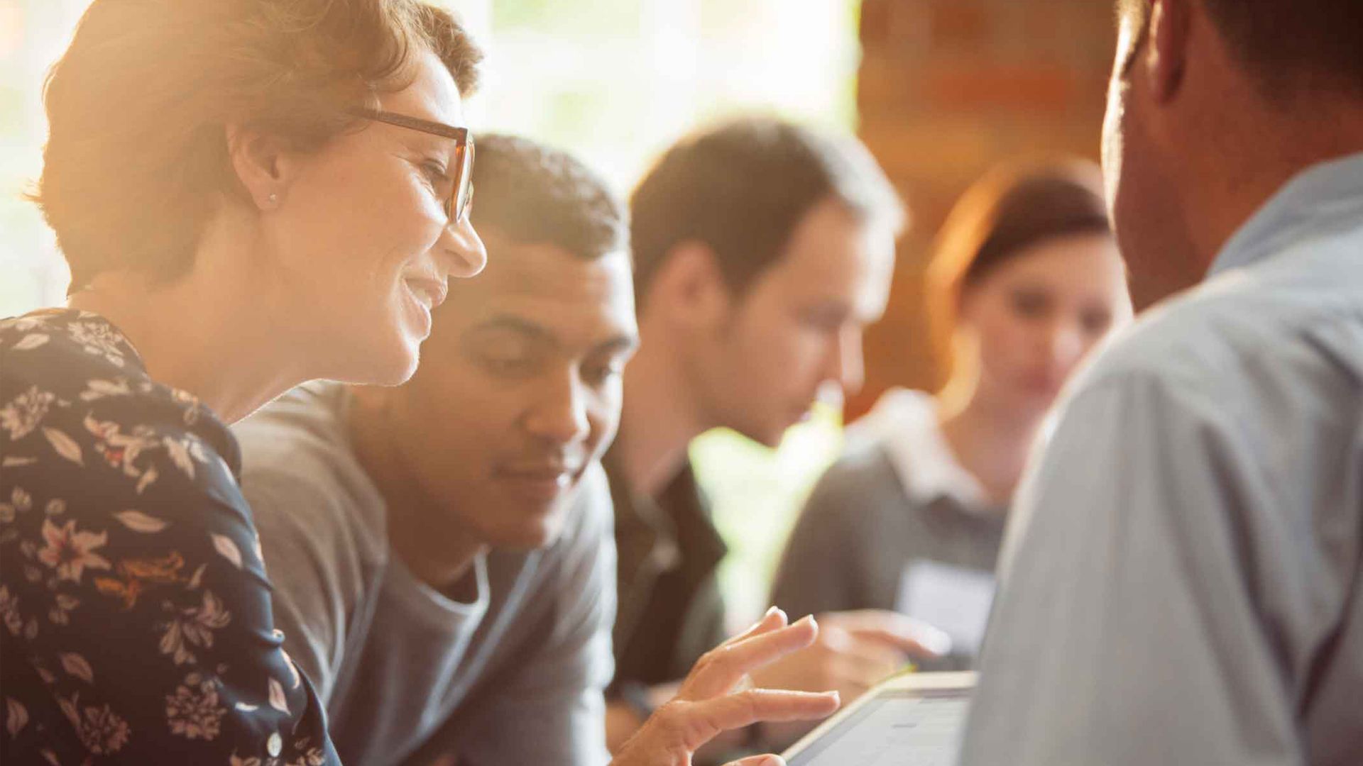 A group of people in a huddle looking at a tablet