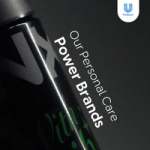 Close-up of a black AXE body spray can with a metallic cap against a dark background with the text ‘Our Personal Care Power Brands’. The Unilever logo appears in the top-right corner.