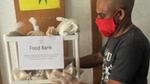 Man in red mask next to Food Bank shelf