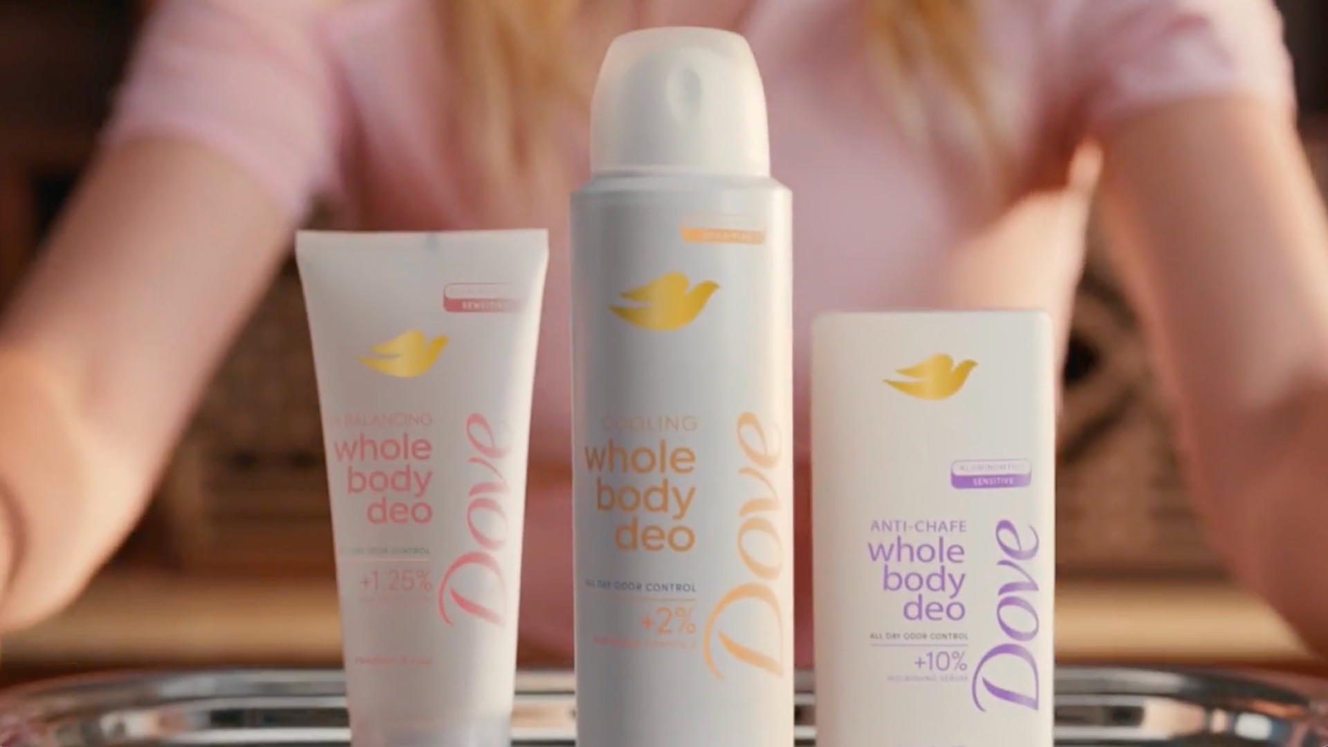 Three Dove Whole Body Deo products displayed on a tray with a person in the background, featuring cooling and anti-chafe variants.