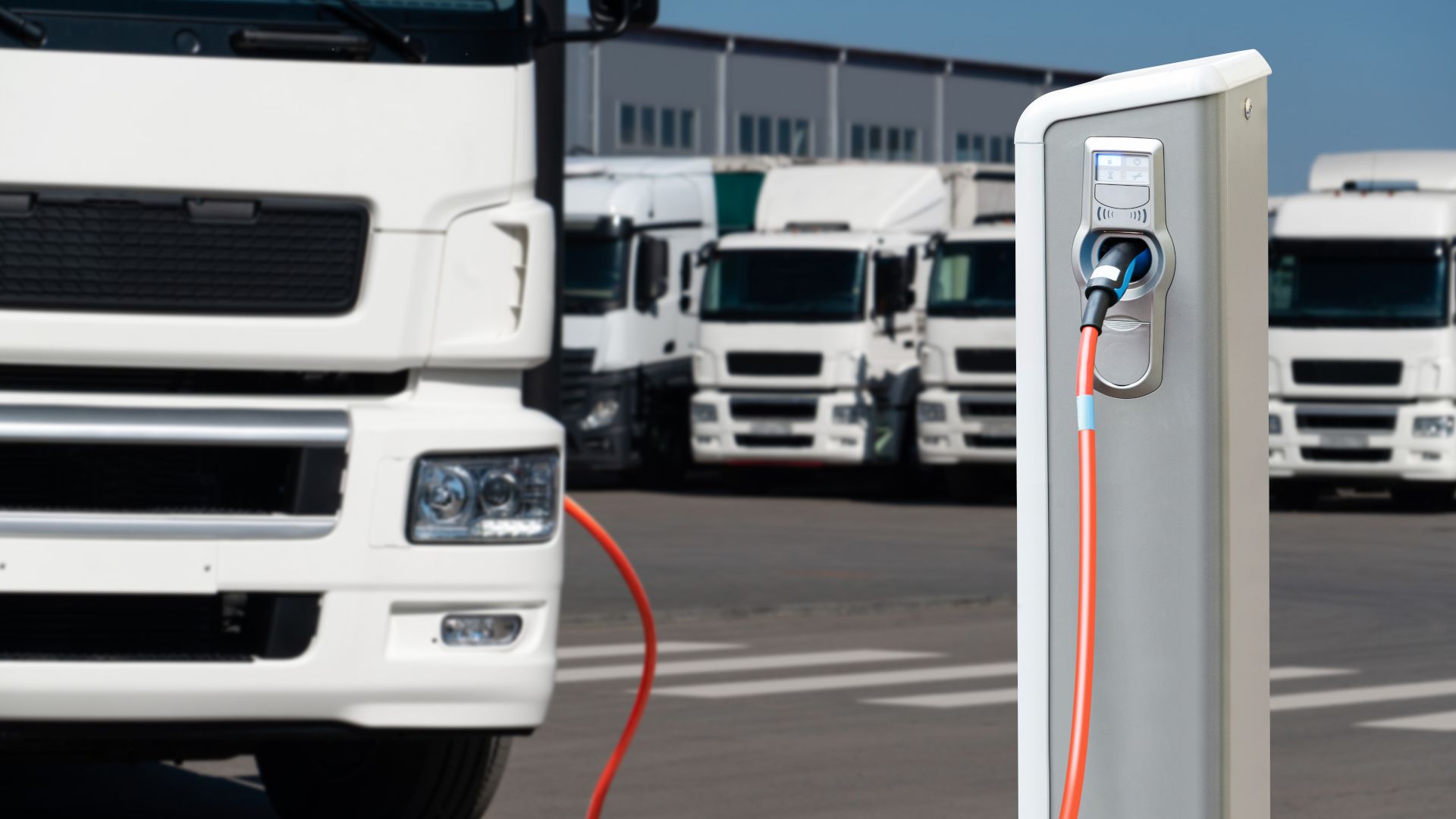 An electric truck recharges, with a fleet of electric trucks in the background. 