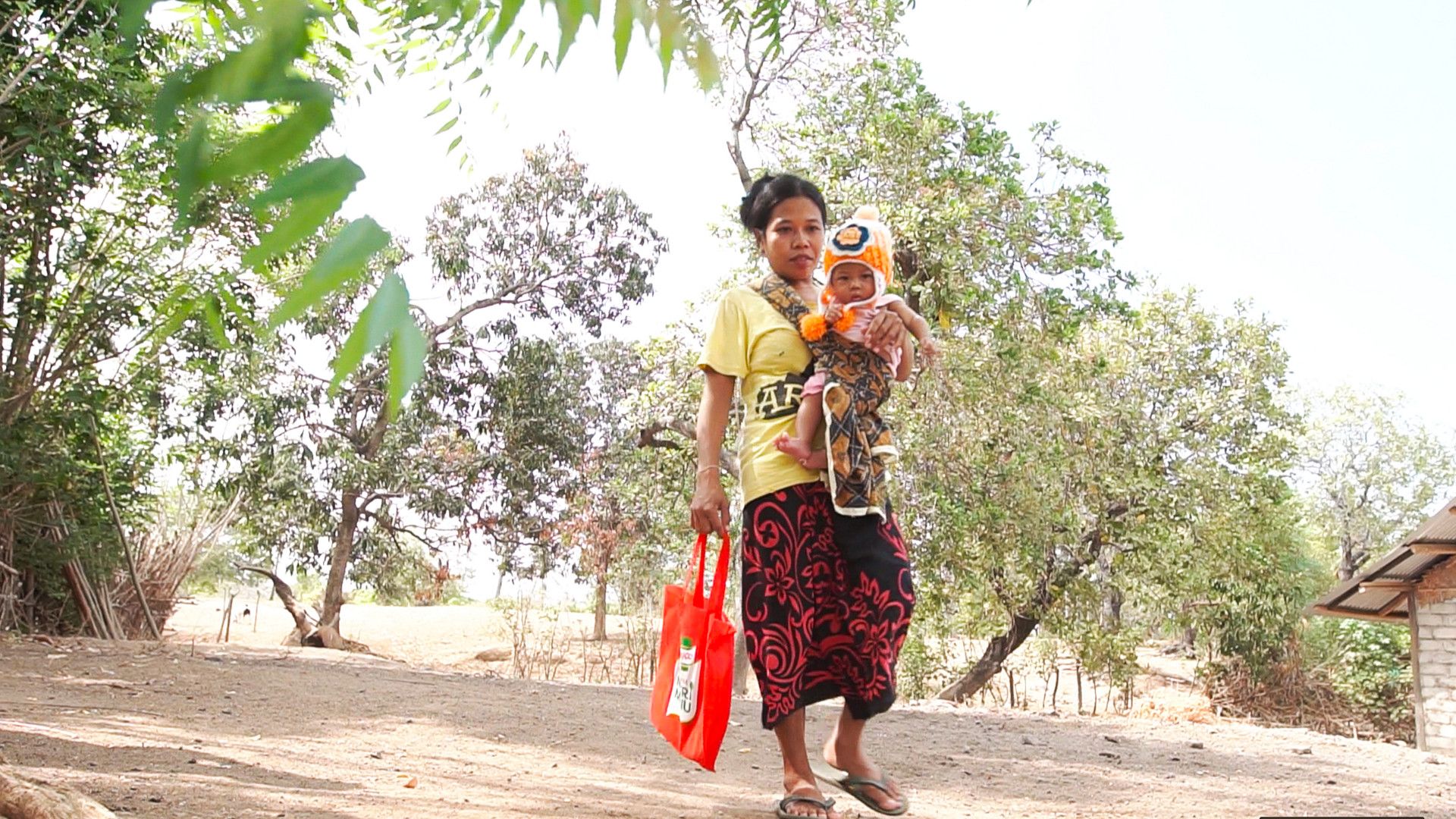 Lady with a baby in her arms carrying a Knorr shopping bag