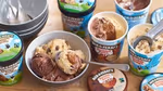 Various tubs of Ben & Jerry’s ice cream with several scoops in a bowl.