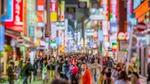 An Asian street scene at night with people walking between lit up signs.
