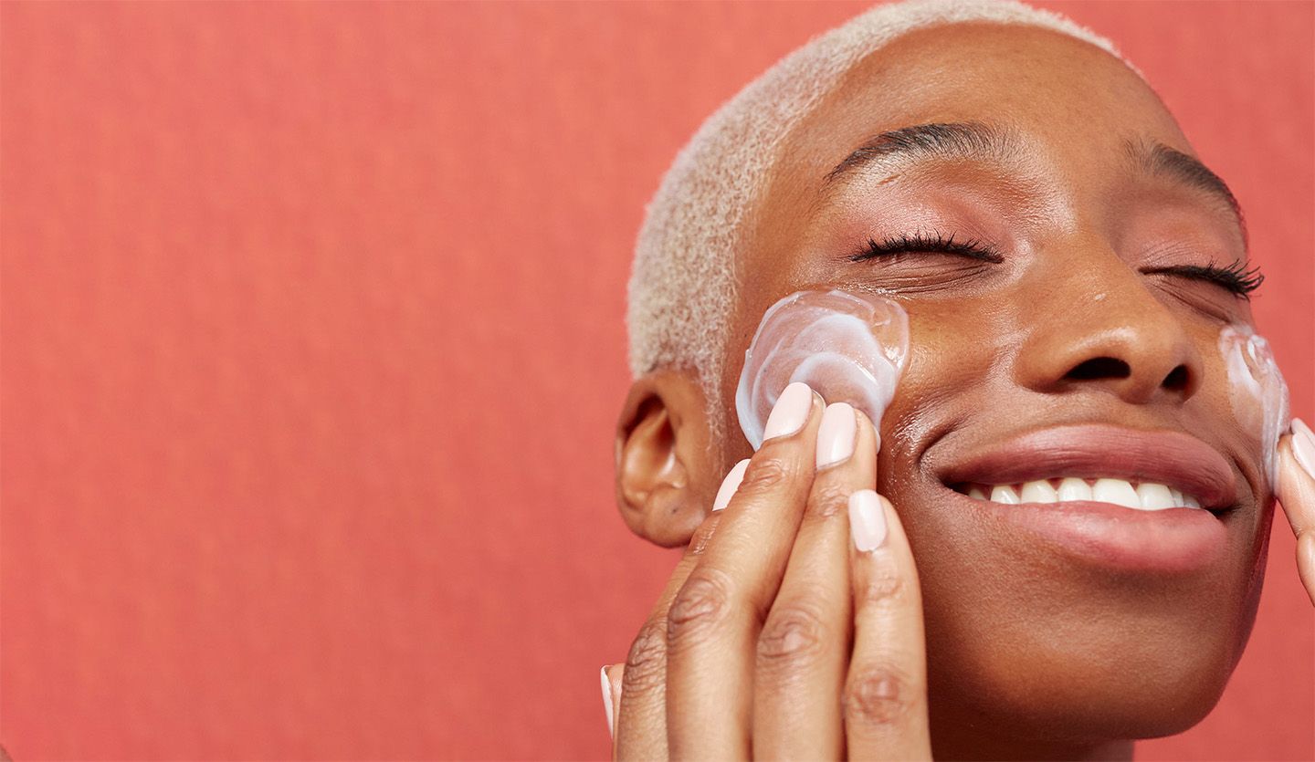 Woman smiling and moisturising her face