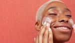 Woman smiling and moisturising her face