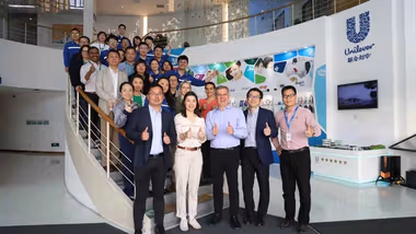 Reginaldo Ecclissato smiling with a team of colleagues on a staircase