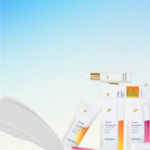 A clean product image showing an arrangement of Dove skincare items—white tubes and bottles with gold and coloured accents—set against a soft blue gradient background. A white cosmetic pad appears on the left, creating a minimal and bright layout focused on the products.