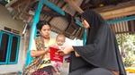 Mother holding a baby being shown a brochure by another woman