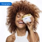 Person holding a Dove body care product in a bathroom setting with white tiles in the background.