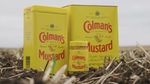 An image of two tins of Colman’s mustard powder and a jar of mustard photographed in a field.