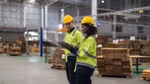 Man and woman in hard hats having a conversation in a warehouse