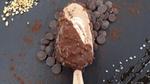 New Vegan Hazelnut Crunch stick sitting on a dark table surrounded by dark chocolate chips